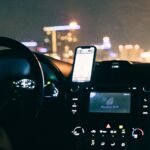 Car dashboard with phone showing GPS directions during night time drive.